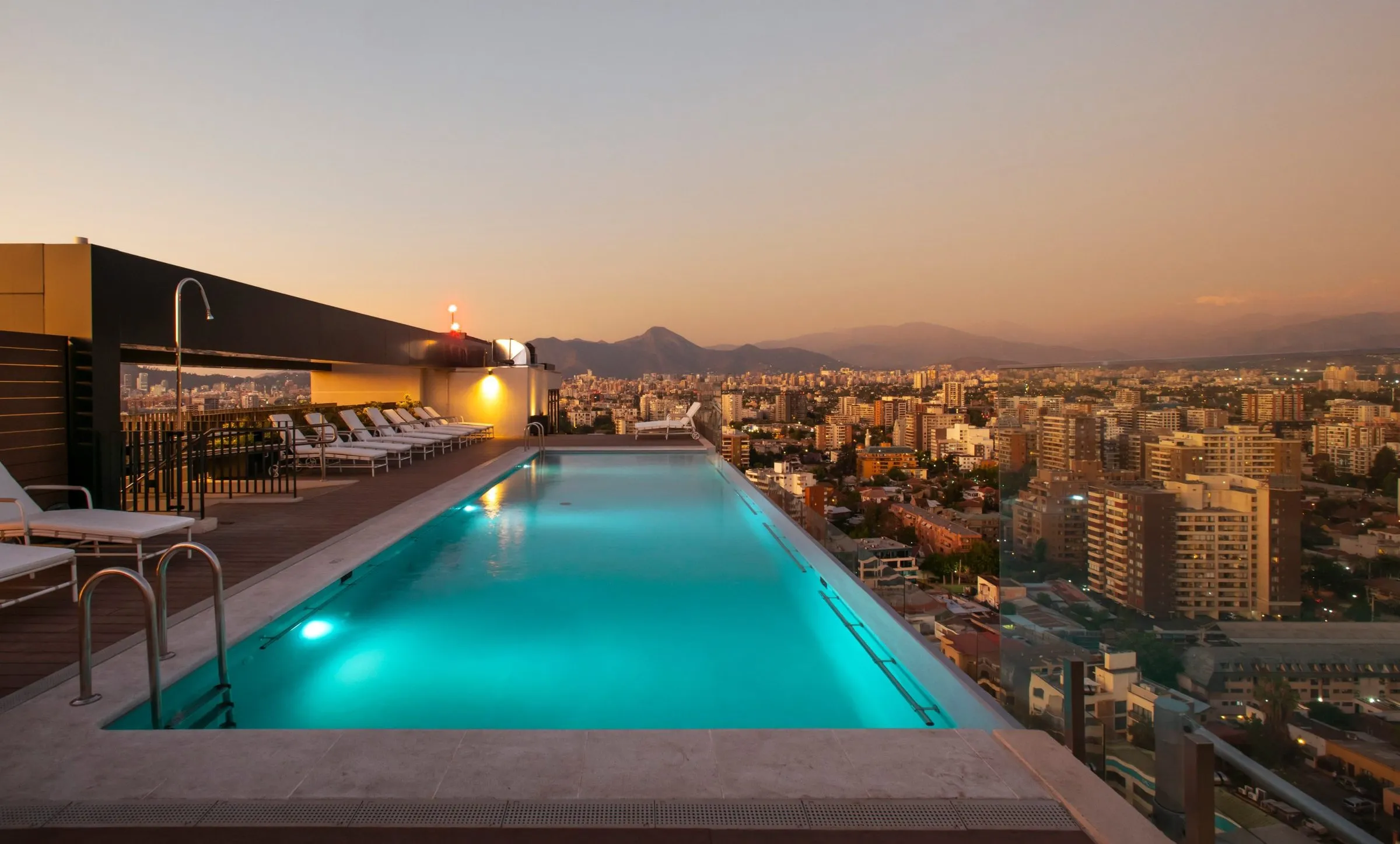 Piscina en la azotea de SOMMA Plaza Ñuñoa al atardecer, con vista a Santiago